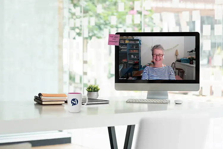 Schreibtisch in einem hellen Büro mit einem Bildschirm, auf dem ein offenes Zoom Meeting mit Susanne Jestel zu sehen ist, als Symbolbild für den Marketing Talk mit Susanne Jestel.