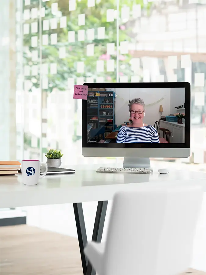 Schreibtisch in einem hellen Büro mit einem Bildschirm, auf dem ein offenes Zoom Meeting mit Susanne Jestel zu sehen ist, als Symbolbild für den Marketing Talk mit Susanne Jestel.