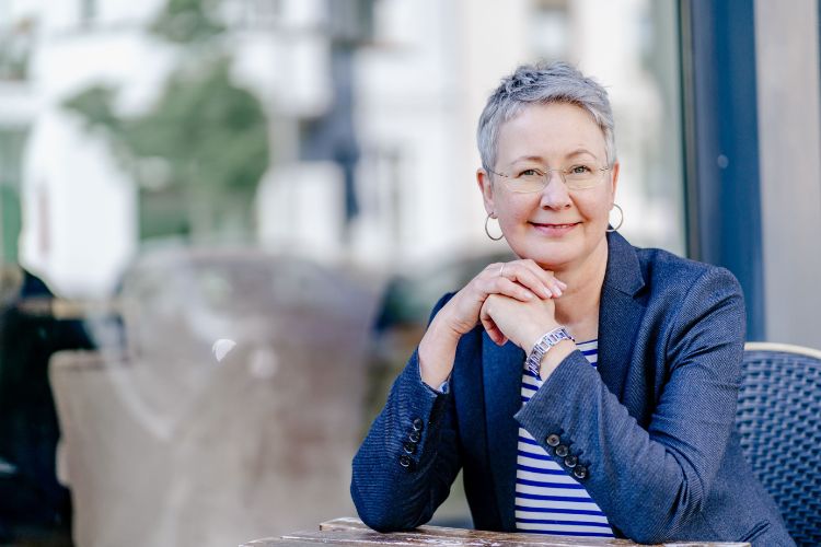 Susanne stützt die Ellenbogen auf den Tisch